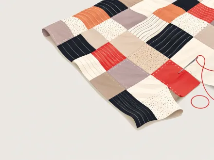 A patchwork quilt of different fabrics, with a needle stitching in one more red square