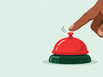 A finger hovers just above a red service bell on a plain surface, about to press it.