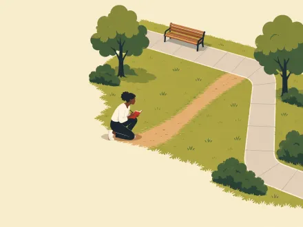 A worn dirt path cutting across the grass beside a paved park path, with a person kneeling to take notes